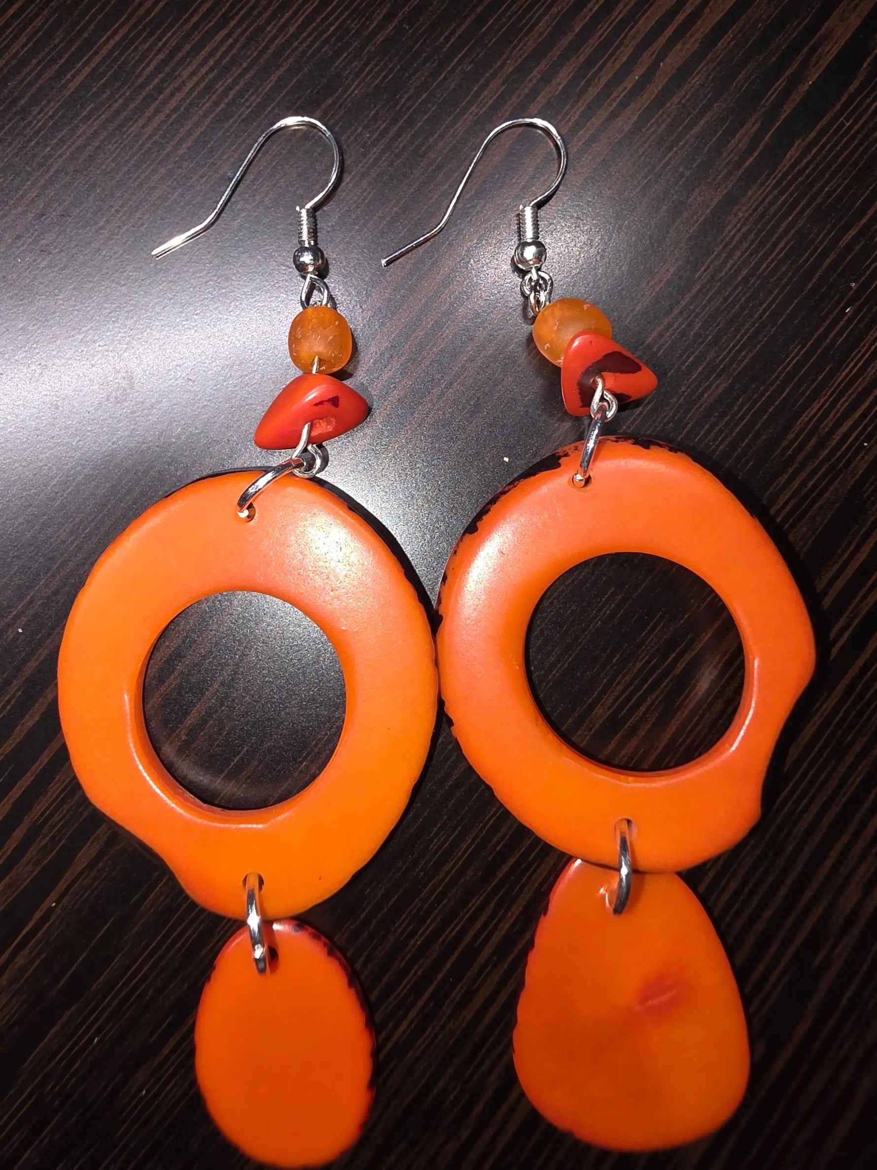 Vibrant pumpkin orange thick hoop ring tagua slice earrings with a glossy finish and layered bead accents