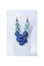 A layered remy vibrant tagua necklace featuring teal and deep blue teardrop beads with dark blue pearl loop accents