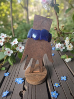 Rich navy blue carved vegan tagua nut vegetable ivory bracelet displayed on rustic wooden hand stand forest seed bracelets