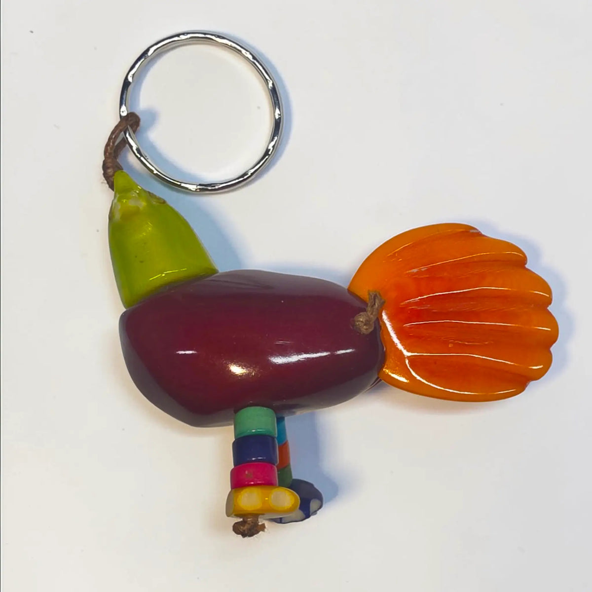 Colorful glossy hand-carved tagua animal keychain shaped like a stylized bird with green beak and orange tail