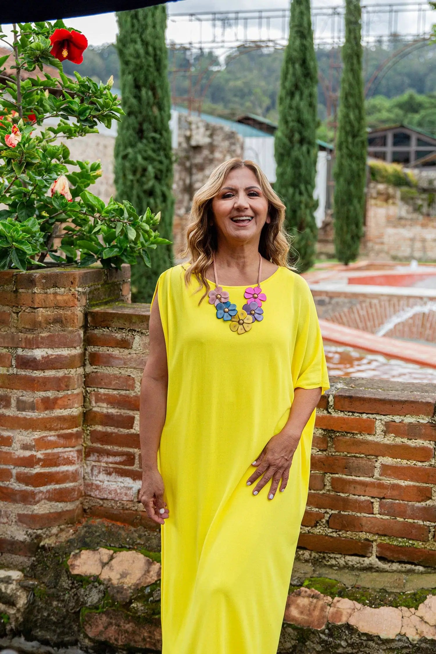 A vibrant yellow sleeveless maxi dress with a flowing fit and pastel multi floral embellishment at the neckline
