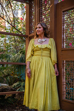 A flowing yellow linen dress with puffed sleeves and square neckline paired with rosalia necklace pastel multi