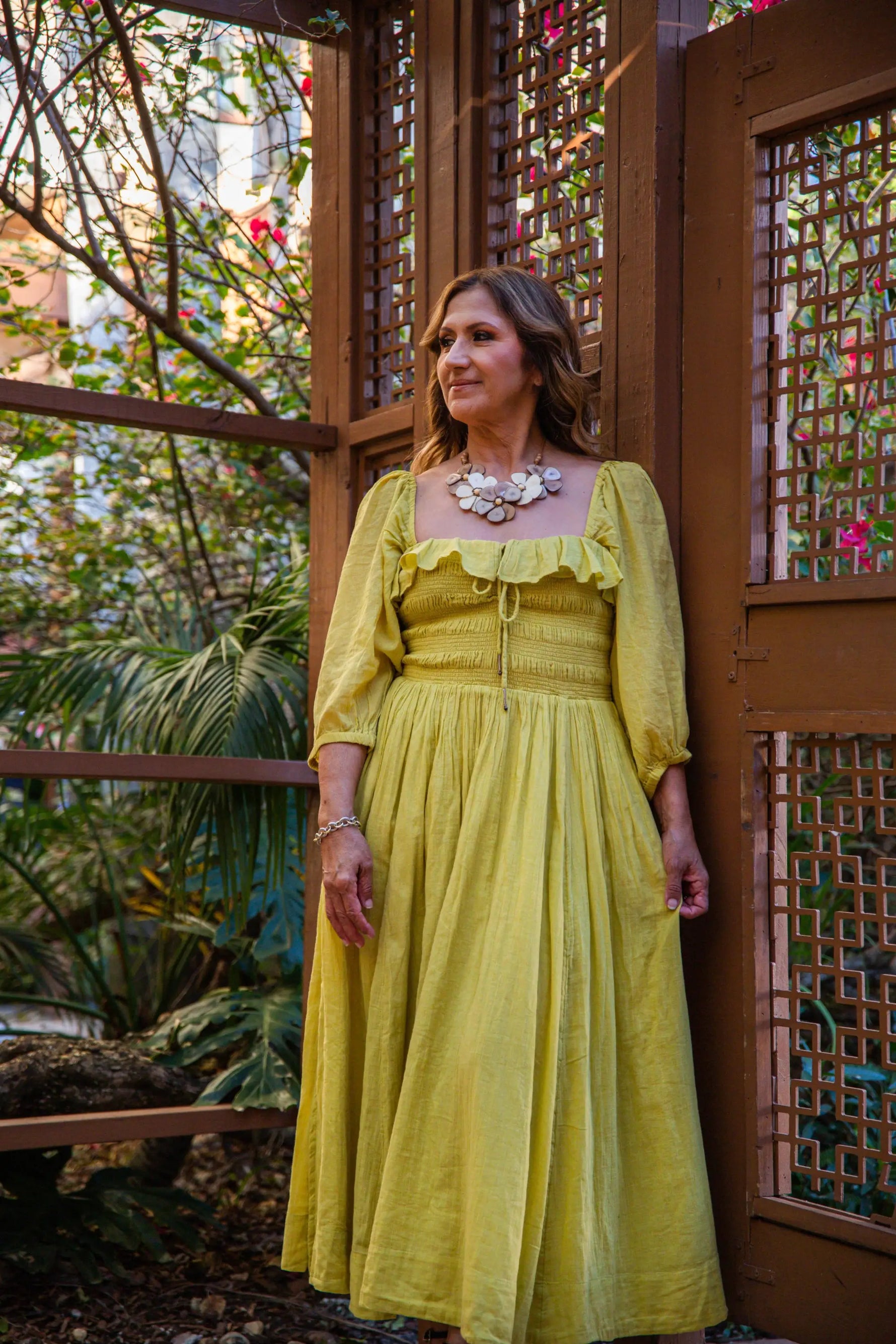 A flowing yellow linen dress with puffed sleeves and square neckline paired with rosalia necklace pastel multi