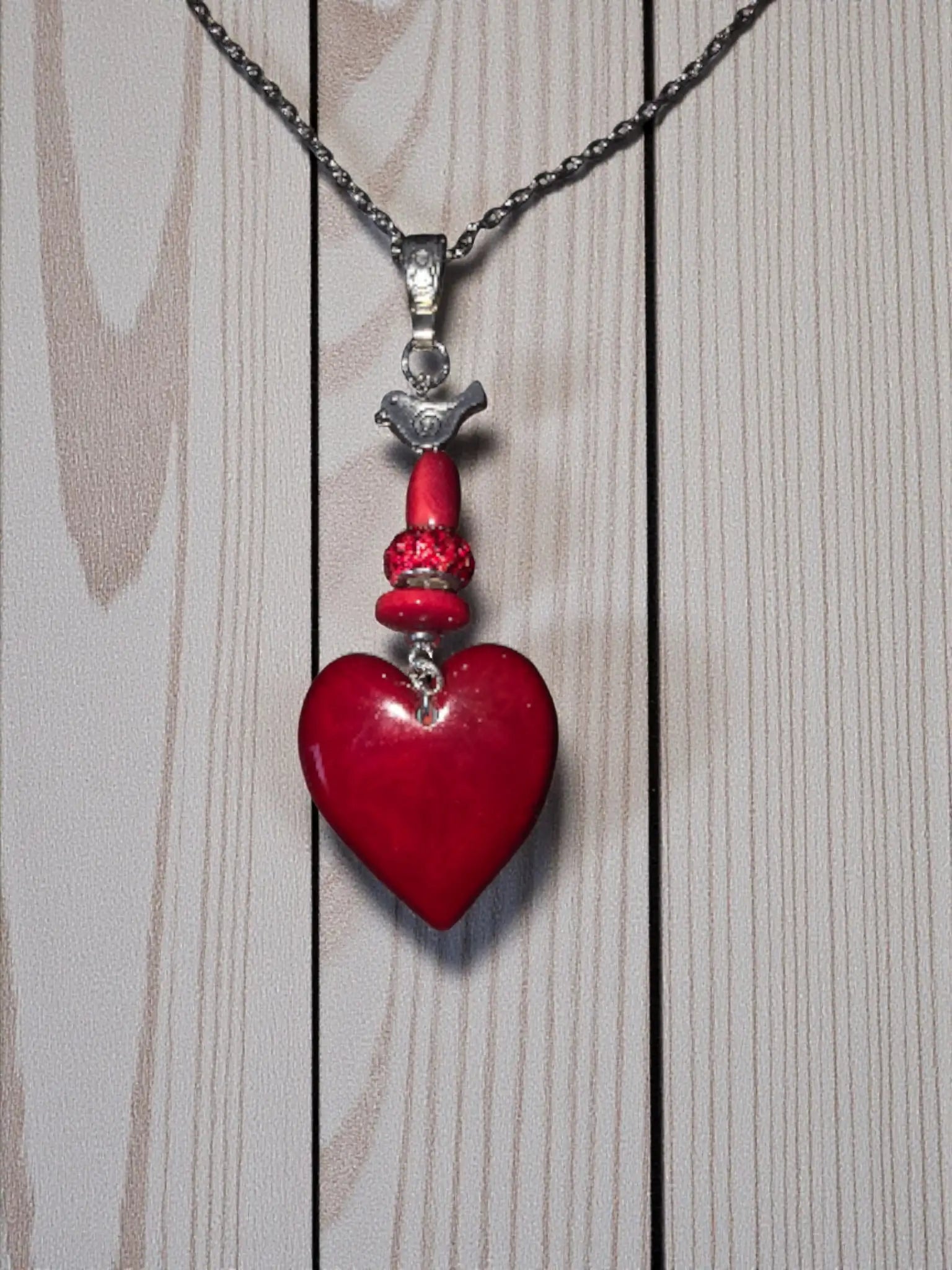 Ruby red carved tagua heart pendant necklace with silver bird charm and beaded accents fair trade jewelry