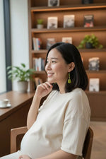 A woman wearing a soft white t-shirt showcasing sage cut perfectly imperfect polished pair of tagua earrings