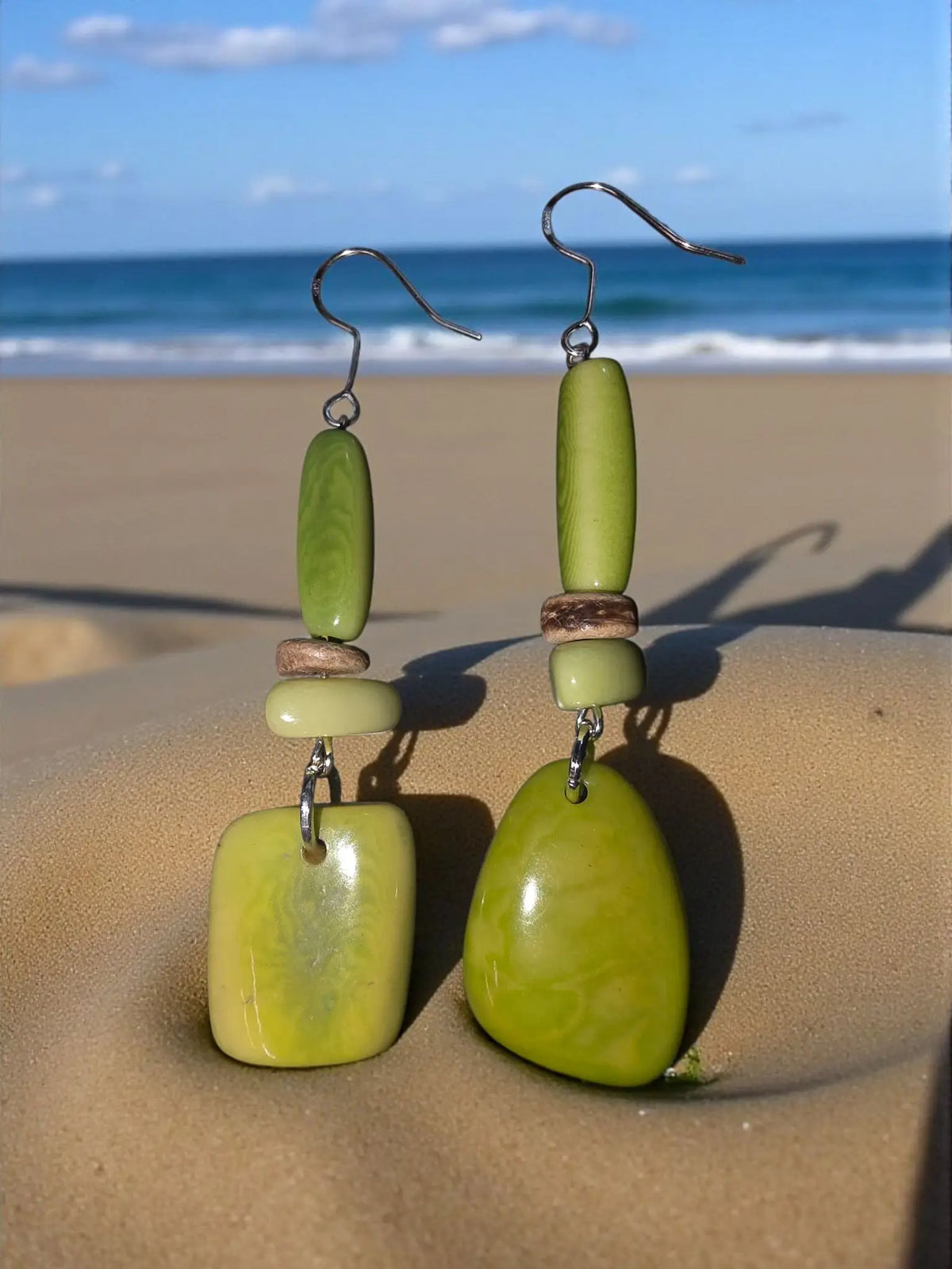 Green stone drop earrings with layered oval and teardrop beads accented by small wooden discs in a polished tagua design