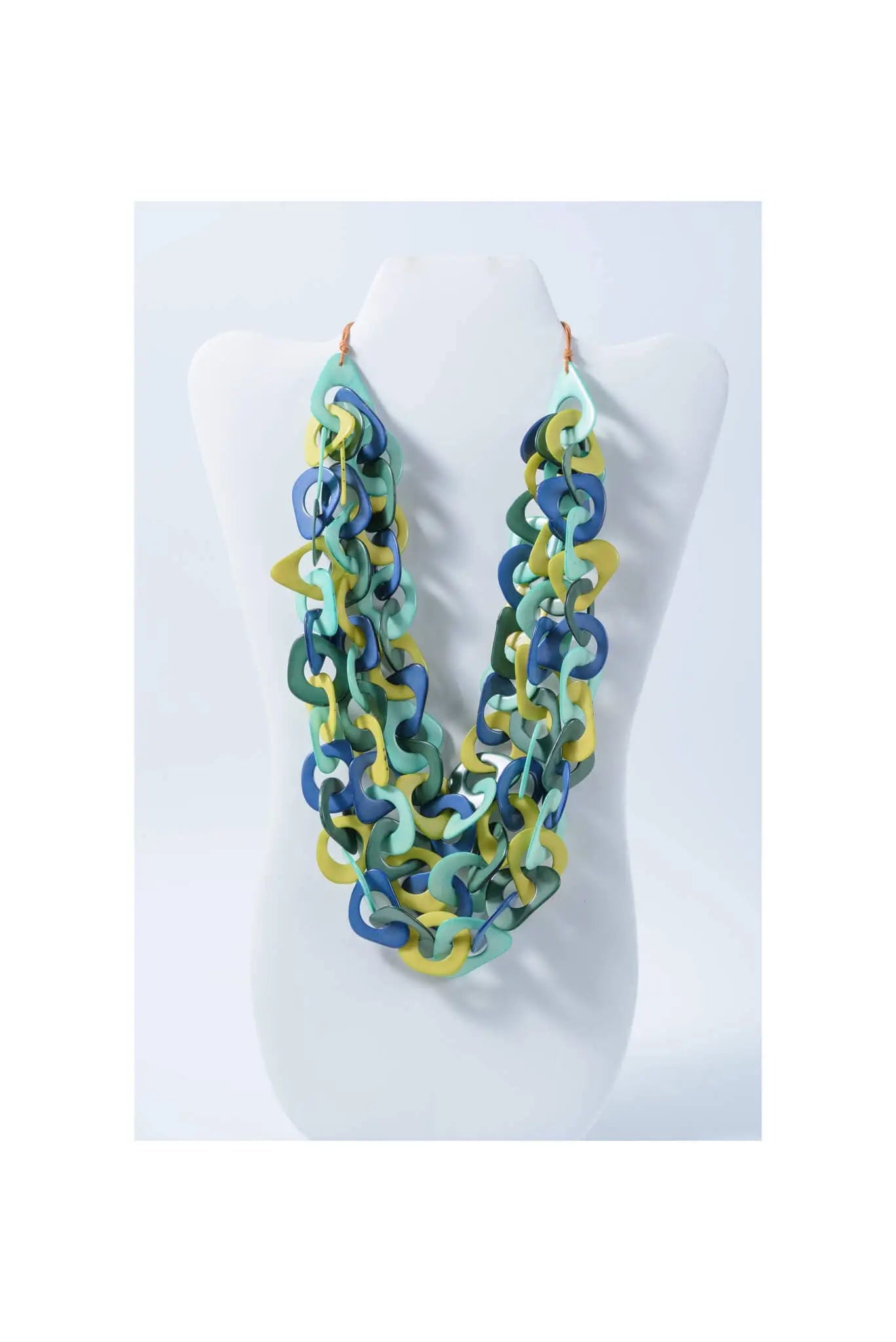 A vibrant three-stranded scarf tagua necklace with interlocking teal, blue, and yellow links made from natural tagua