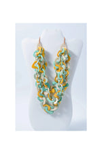 A vibrant three-stranded scarf tagua necklace with yellow teal and cream interlocking eco-friendly links