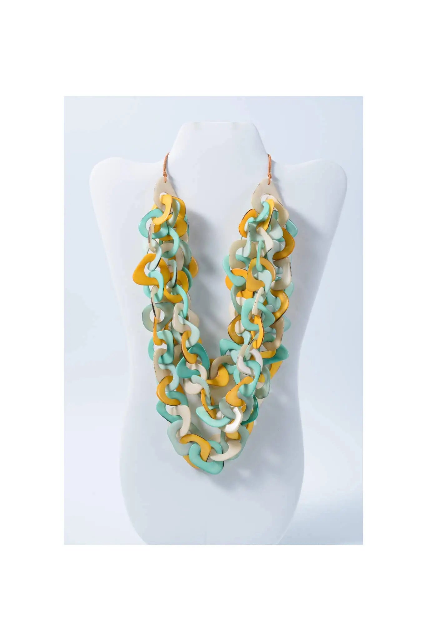A vibrant three-stranded scarf tagua necklace with yellow teal and cream interlocking eco-friendly links