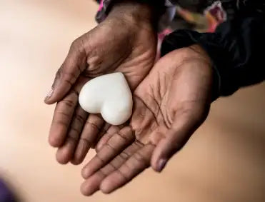 A smooth, white heart-shaped object held gently in two hands.