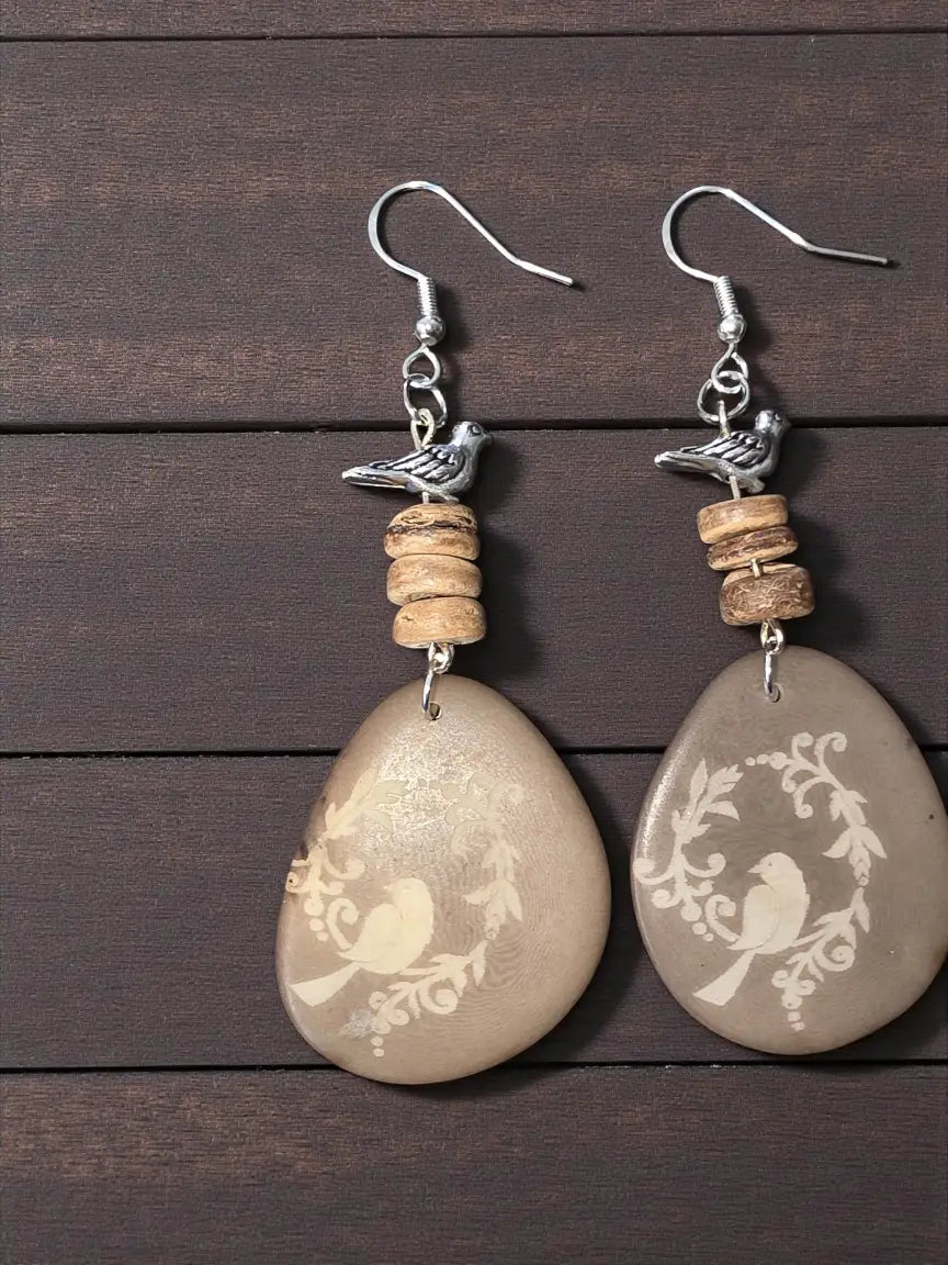 Beige teardrop tagua earrings with engraved bird and vine design silver bird charms and stacked wooden beads