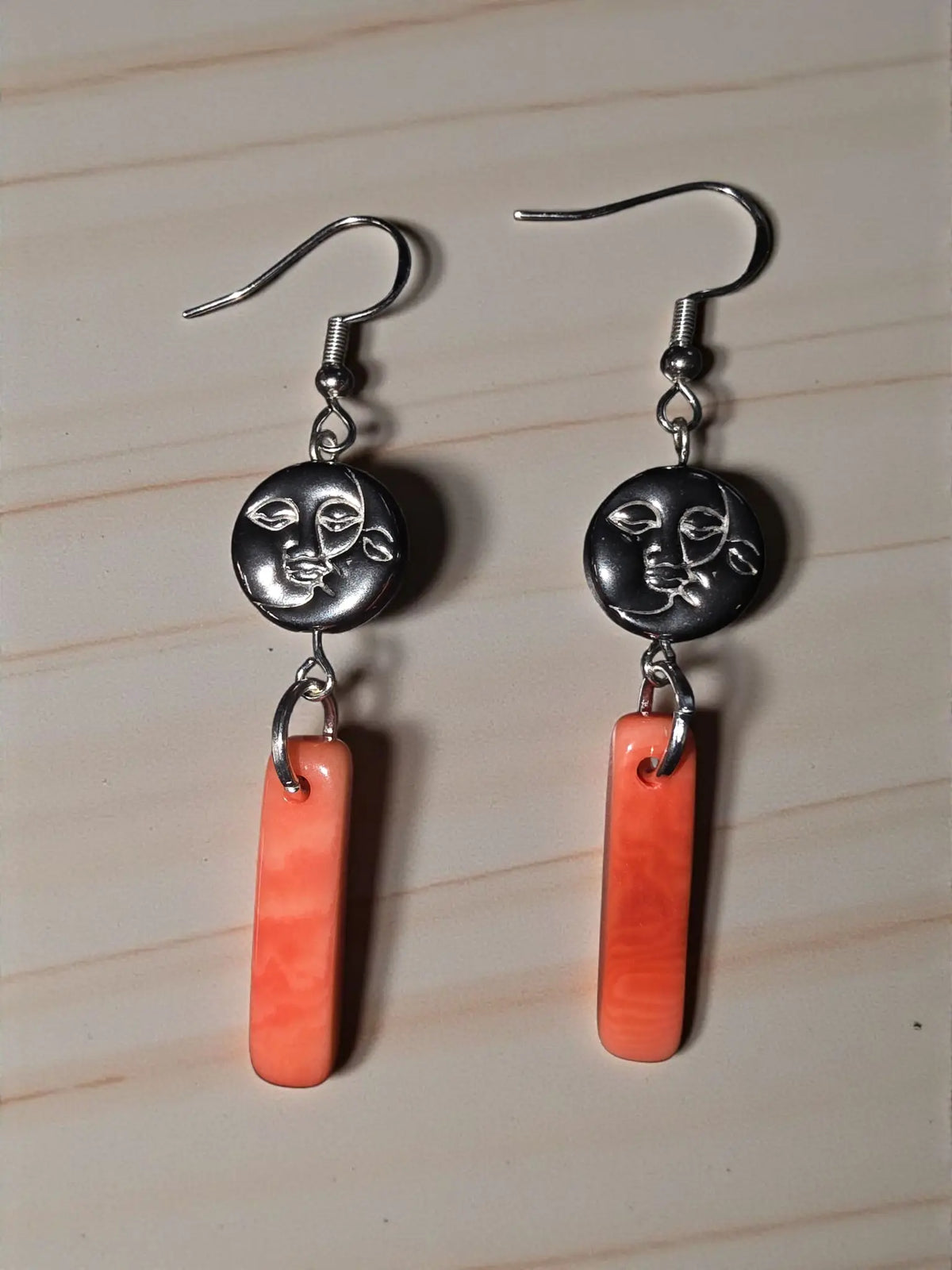 Silver dangle earrings with black moon face charm featuring two faces above orange peach melon tagua pendant