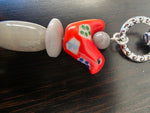 A vibrant red glossy glass shoe keychain with green and blue details from the super thick tangerine tagua carved heart bag charm collection