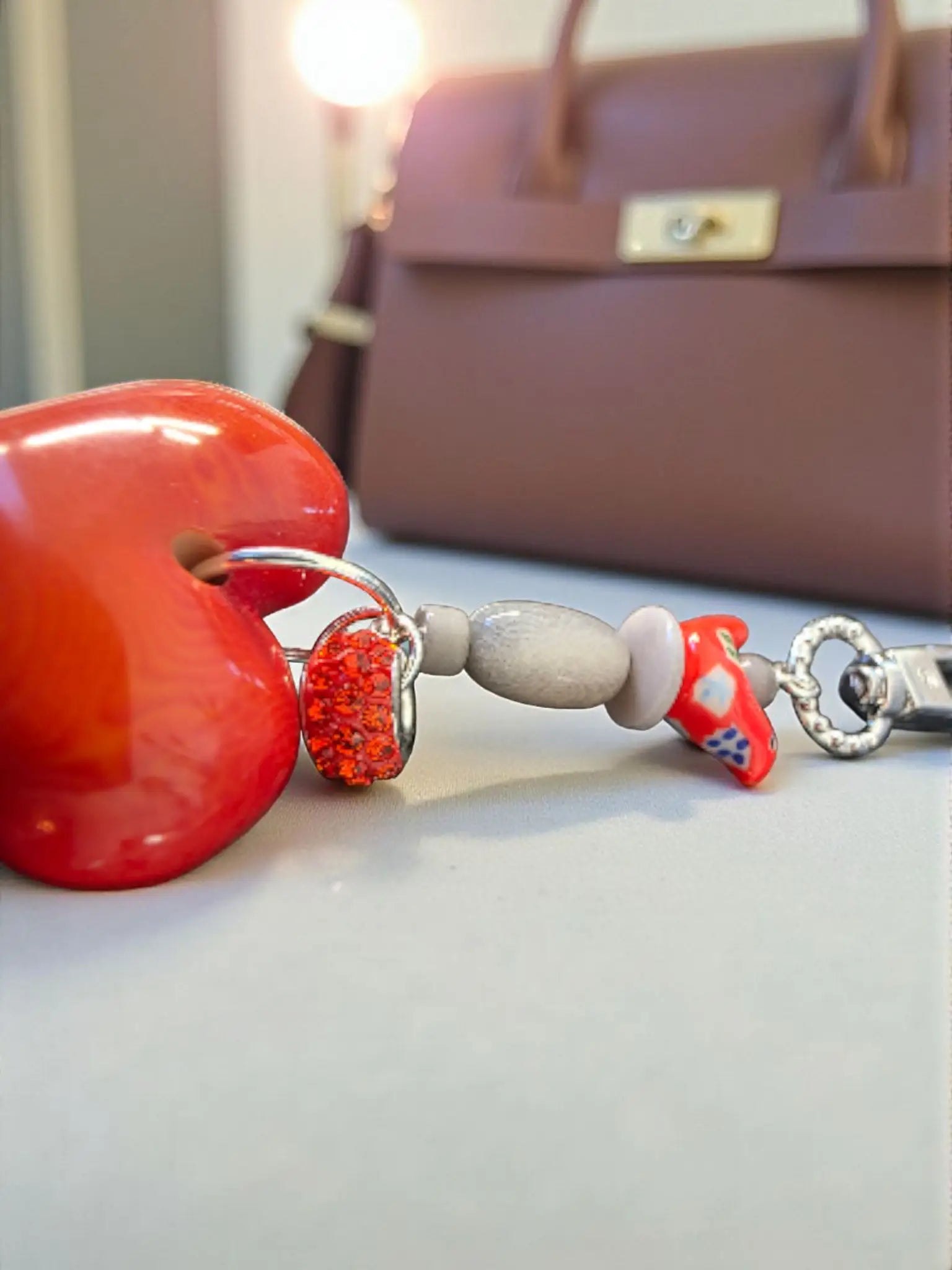 Vibrant red glossy heart-shaped carved tagua keychain with silver chain and ceramic folk art bird bead charm