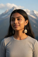 Silver-toned oval drop earrings with subtle engraved pattern and metal hooks sweet songbird singing on a vine tagua