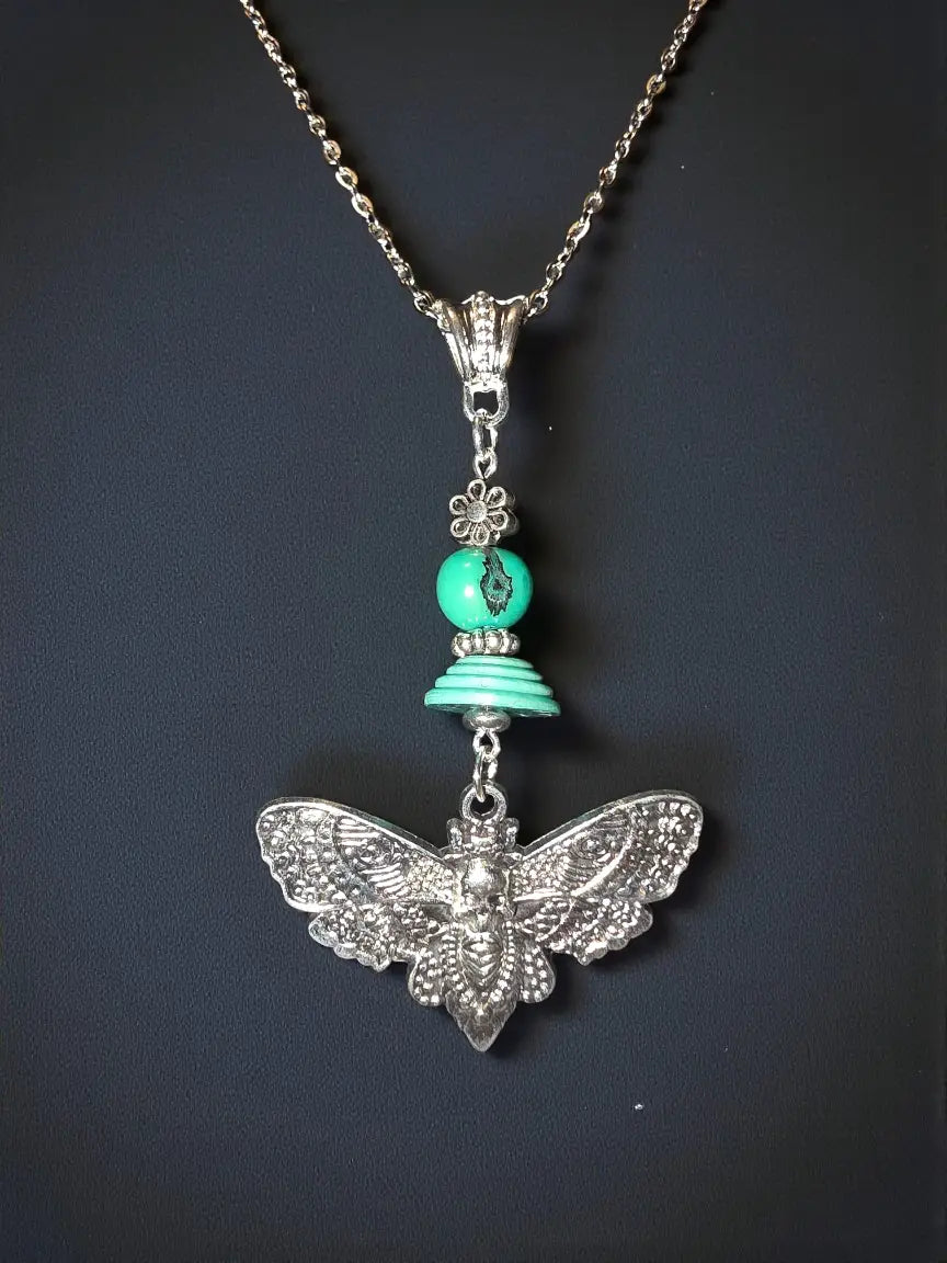 Silver pendant necklace with turquoise beads and intricate cicada moth charm featuring tagua beads accent