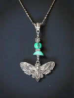 Silver pendant necklace with turquoise beads and intricate cicada moth charm featuring tagua beads accent