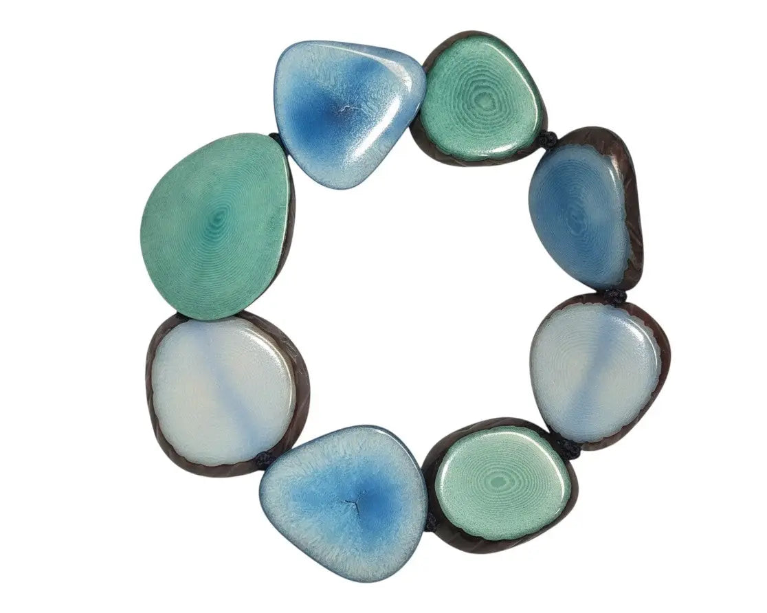 A tagua stretch bracelet with glossy blue and green ceramic beads edged in dark brown dyed with vegetable dyes