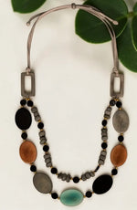 A tagua nut double strand adjustable necklace with silver clasps and oval beads in black brown gray and teal with gold accents