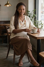 A woman wearing a cream v-neck top with a triple-strand tagua nut statement necklace on a cotton cord