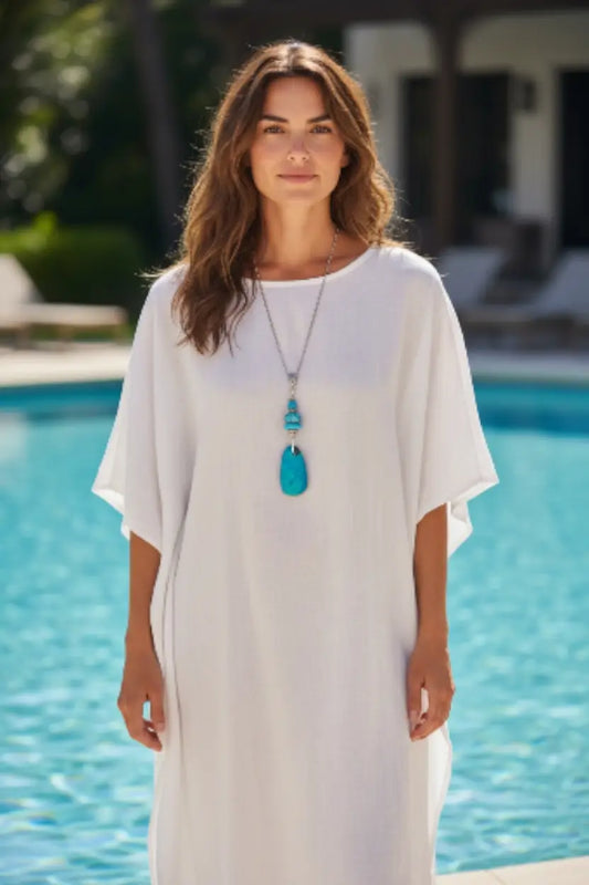White flowing maxi dress with round neckline and short sleeves paired with turquoise blue sustainable tagua nut necklace