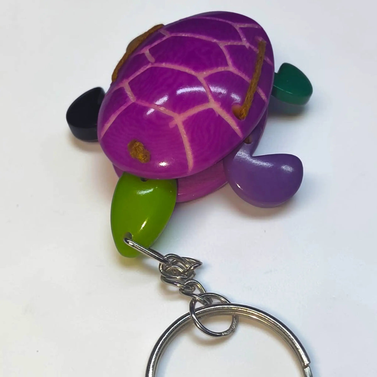 Purple wooden turtle keychain with green and black accents from hand-carved tagua animal keychains collection