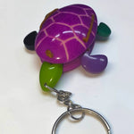 Purple wooden turtle keychain with green and black accents from hand-carved tagua animal keychains collection