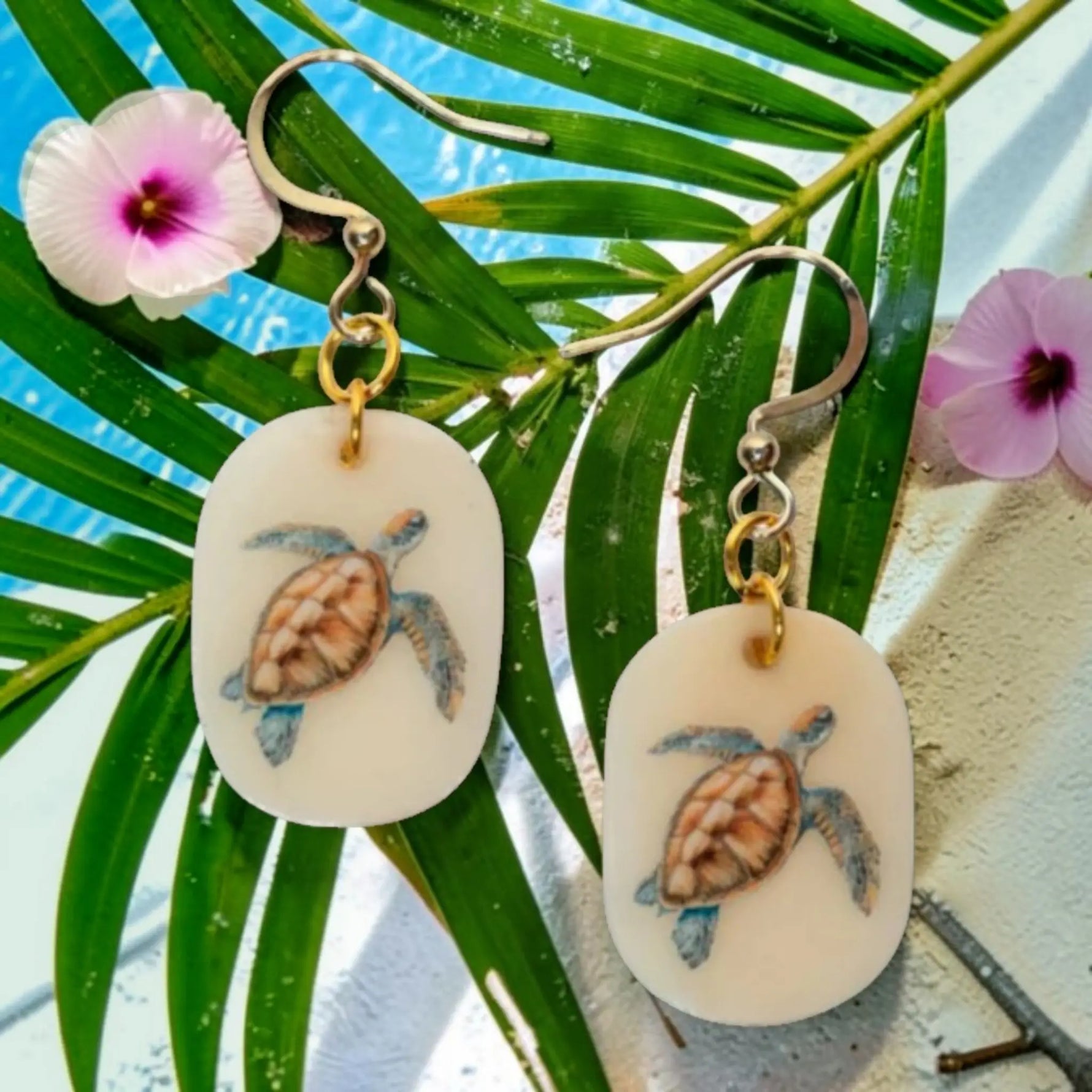 Cream-colored oval turtle tagua nut eleni earrings feature hand-painted brown and blue sea turtle designs