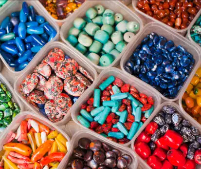 A vibrant assortment of colorful beads in various shapes, sizes, and materials displayed neatly in clear plastic containers.