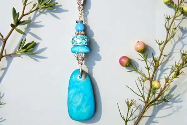 Turquoise pendant necklace with beads on a light background