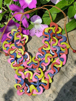 Vibrant three-stranded tagua necklace with glossy pink yellow orange and blue carved eco friendly links from ecuador