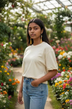 Cream-colored loose-fitting cotton t-shirt with rolled-up sleeves paired with yellow orange crush baguette tagua earrings with tibetan amulet sun bead