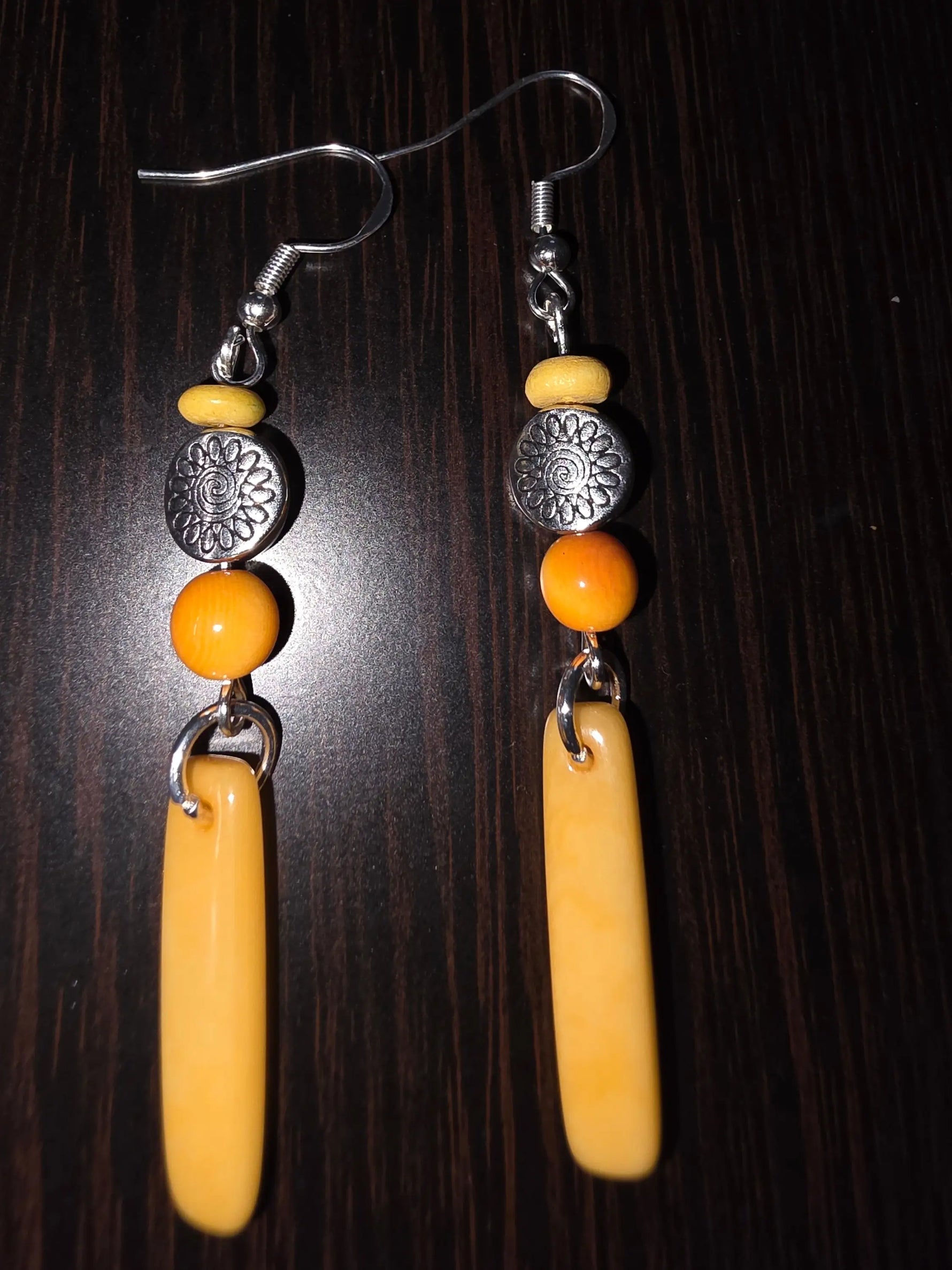 A pair of yellow orange crush baguette tagua earrings with silver hooks, yellow and orange beads, and tibetan amulet sun discs