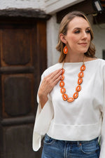 Bright orange oval tagua nut bead necklace with smooth glossy finish complementing yoli earrings celeste ivory