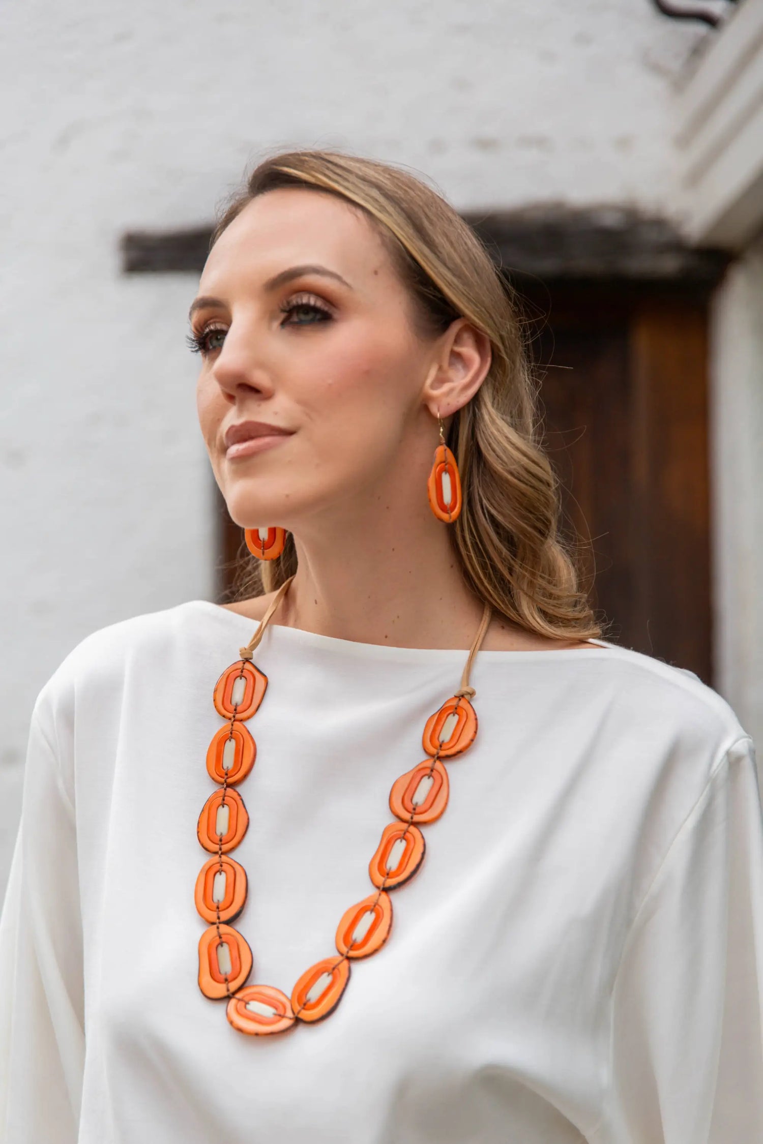 Bright orange oval pendant necklace with a light brown cord from yoli necklace multi collection